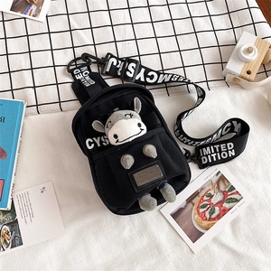 Detailed flat lay of a black canvas chest bag featuring a cute plush bull doll pendant