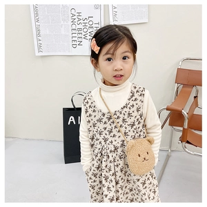 Detail of child's outfit with floral dress and a cute brown plush bear crossbody bag