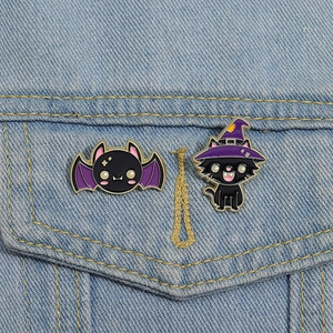 Cute black cat witch and purple bat enamel pin set on blue denim jacket pocket