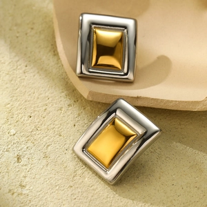 Close-up of square geometry earrings featuring dual-tone gold and silver polished finish