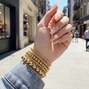 Set of five 18K gold plated beaded stretch bracelets featuring graduated bead sizes and high polish