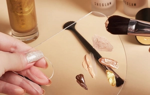 Macro view of clear acrylic makeup mixing palette with foundation and liquid cosmetics
