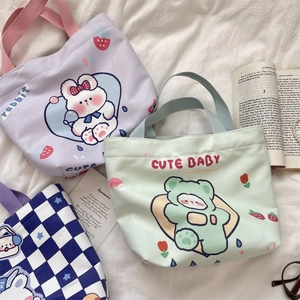 Flat lay of colorful canvas tote bags with cute rabbit and bear prints on white cloth