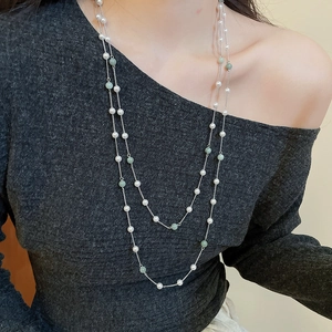 Primo piano di una collana a due strati con perle verdi e perle su una modella