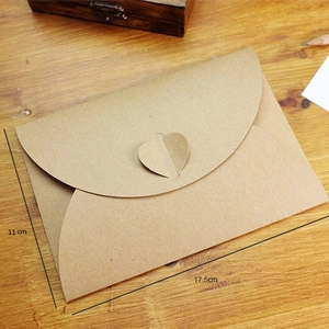 Brown kraft paper envelope with heart buckle and 11x17.5cm dimensions on wood desk