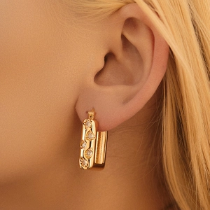 Macro shot of gold-plated rectangular earring set with clear zircons on a model