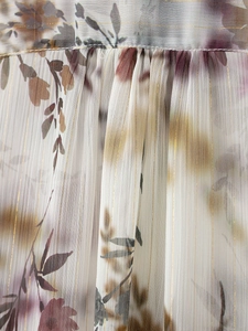 Dettaglio del tessuto in chiffon con fili dorati e stampe floreali ad acquerello