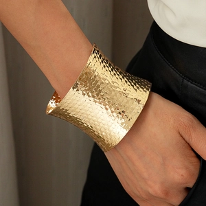 Close-up of wide gold woven texture cuff bracelet with a metallic geometric pattern