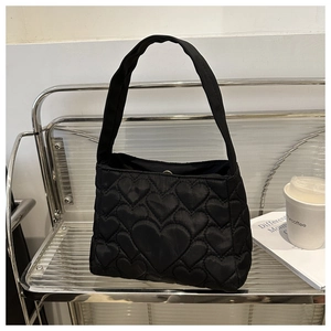 Détail d'un sac cabas noir matelassé avec des motifs créatifs cousus en forme de cœur