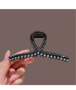 Close-up of black rhinestones and grey pearls on a twist-knot hair claw clip