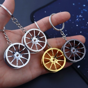 Handheld display of alloy car wheel rim keychains in silver, gold, and gunmetal gray colors