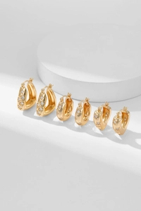Detailed view of three pairs of gold U-shaped hoop earrings with inlaid star zircon