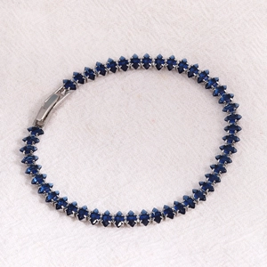 Macro detail of deep blue marquise-cut zircon stones set in silver tennis bracelet