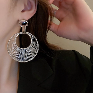 Close-up of a model wearing large hollow silver hoop earrings with a metallic finish