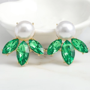 Macro shot of gold earrings with large white pearl and green marquise crystals