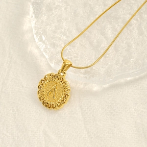 Collana con ciondolo tondo dorato con lettera A sbalzata e bordo in pizzo vintage