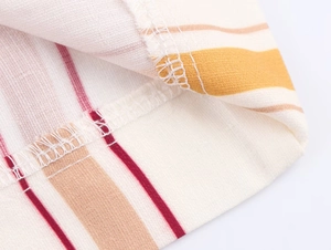 Macro de tissu rayé montrant les coutures surjetées et la texture tissée de qualité