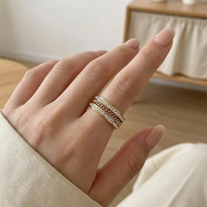 Vue détaillée d'une bague chaîne dorée et d'anneaux sertis de strass sur une main