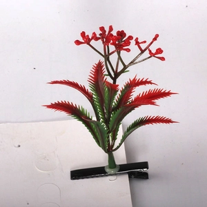 Detail of a sprout hair clip featuring a vibrant red flower and jagged green leaves