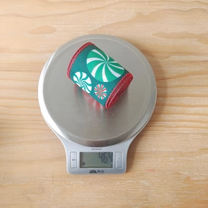 Details von dunkelgrünem Weihnachtsband mit Pfefferminzmuster, 46,4 g schwer auf einer Waage