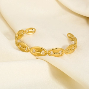Macro shot of gold hollow heart bangle on cream silk fabric highlighting the polished finish