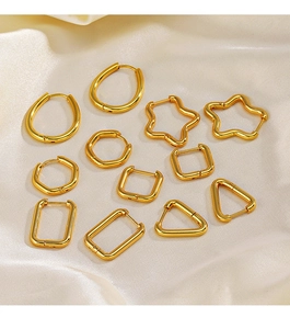 Close-up of six pairs of gold geometric earrings on elegant light-colored silk fabric