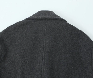 Détail du col et de l'épaule d'un manteau en laine gris foncé au tissu texturé