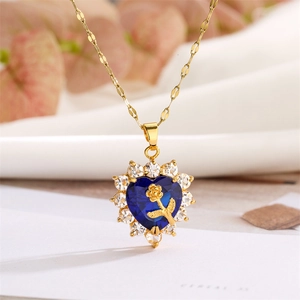Detail of a gold heart pendant with a blue sapphire-like gem and golden rose carving