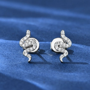 Detail of silver S925 snake earrings with sparkling moissanite on blue fabric
