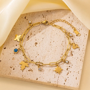 Primer plano detallado de la pulsera de acero inoxidable dorado con dijes de mariposa y hojas