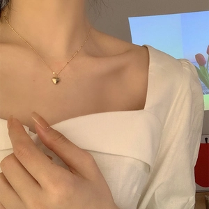 Close-up of minimalist gold heart pendant necklace worn on a woman neck
