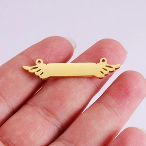 Gold wing bar connector pendant in mirror finish stainless steel held on a finger