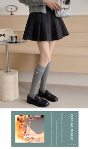 Detail of gray rib-knit over-the-knee socks featuring a white bow embroidery accent