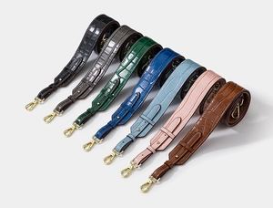 Close-up of crocodile pattern leather straps with gold metal hooks in multiple colors