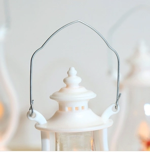 Close-up of white decorative LED lantern with wire handle and vintage plastic top details