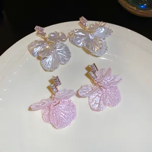 Elegant floral tassel earrings with shell petals and zircon crystals in a ceramic tray