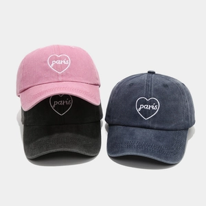 Three washed cotton baseball caps in pink, black, and navy with Paris heart embroidery