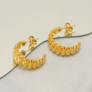 Gros plan détaillé de boucles d'oreilles géométriques dorées en C avec texture