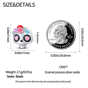 Detail view of silver skull bead with enamel floral pattern next to 25-cent coin for scale