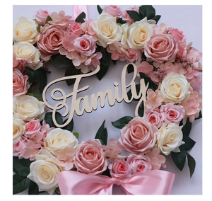 Detail of heart-shaped floral wreath with pink roses, wooden Family sign and satin bow