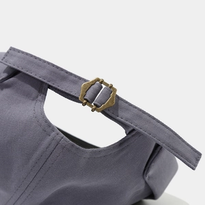 Close-up of adjustable copper buckle and cotton twill fabric on a retro docker cap