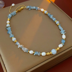 Detail of freshwater pearl and aquamarine necklace on brown leather display case