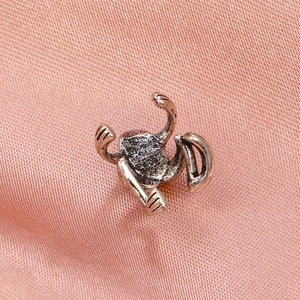Macro detail of vintage silver frog ear cuff on elegant pink silk background