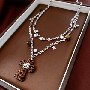 Dettaglio della collana a doppio strato con croce leopardata e perline occhio di tigre