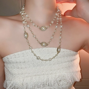 Detail of multi-layer pearl necklace with a rhinestone pendant on a female model
