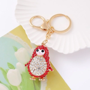 Detailed macro view of a gold penguin keychain with sparkling red and white rhinestones