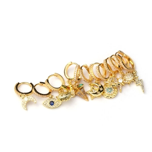 Gold huggie hoop earring set featuring zircon moon star and evil eye charms on white background