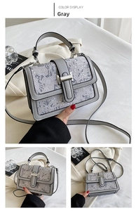 Detail view of grey floral jacquard handbag with silver buckle and leather strap
