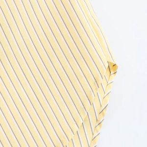 Close-up of the curved hem and fabric texture on a yellow and white striped shirt