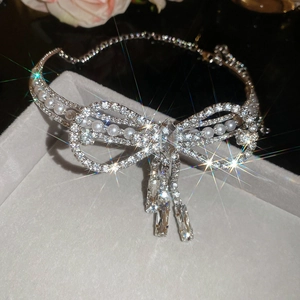 Close-up of silver bow necklace with sparkling rhinestones and pearl tassel in a gift box